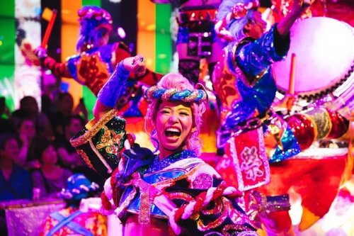 A vibrant performance featuring dancers in colorful costumes, joyfully celebrating with traditional instruments and lively expressions.
