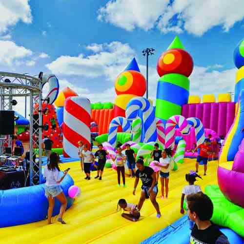 A colorful inflatable playground filled with children playing, surrounded by candy-themed structures and bright decorations.