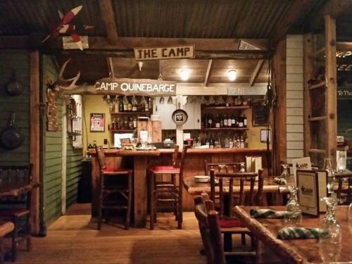 Cozy rustic restaurant interior with a wooden bar, tables, and decor featuring camp-themed elements.