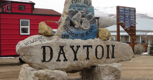 A large stone sign reading "Welcome to Dayton" with a painted depiction of gold discovery in Nevada, 1849.