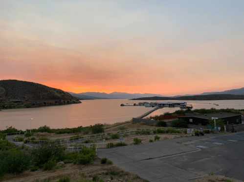 Sunset over a calm lake with mountains in the background and a small marina in the foreground.