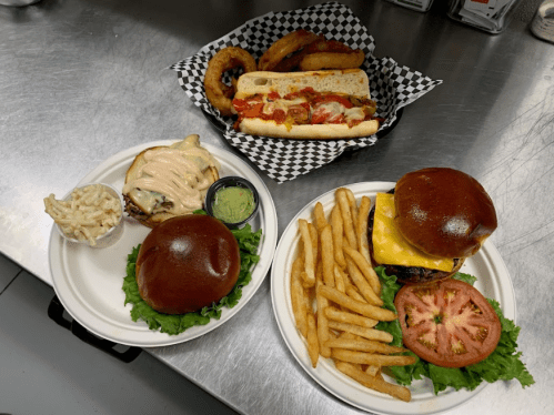 Two burgers with lettuce and cheese, fries, coleslaw, and a hot dog with onion rings in a basket.