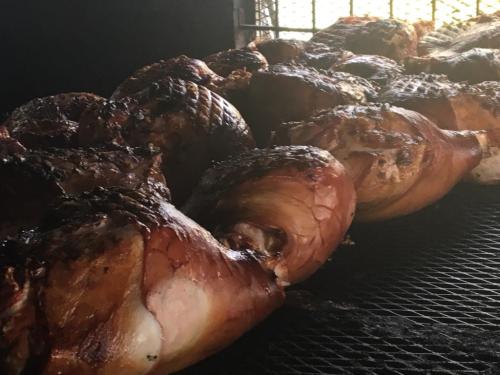 Smoked meat on a grill, showcasing several large, caramelized pieces with a crispy exterior.