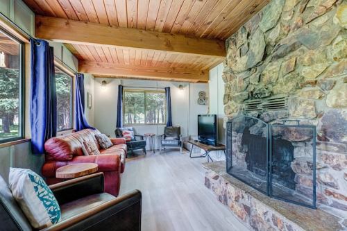 Cozy living room with stone fireplace, wooden beams, large windows, and comfortable seating.