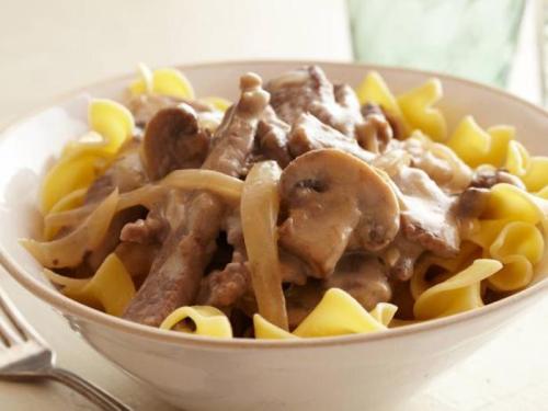 A bowl of egg noodles topped with creamy beef and mushroom sauce.
