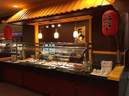 A sushi bar with a variety of dishes displayed under warm lighting and decorative lanterns.