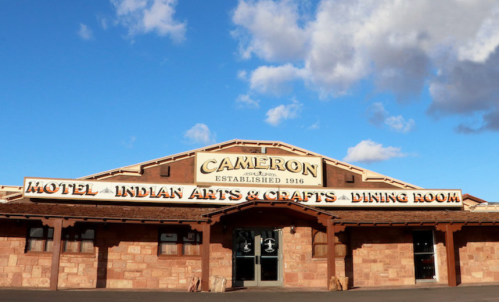 Signage of the Cameron Motel, featuring "Indian Arts & Crafts" and "Dining Room," against a blue sky.