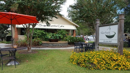Exterior of Sugar Kettle Café featuring outdoor seating, vibrant flowers, and a welcoming sign.