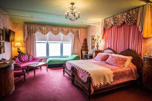 A vintage-style bedroom featuring a large bed, ornate furniture, and colorful decor with a cozy seating area by the window.