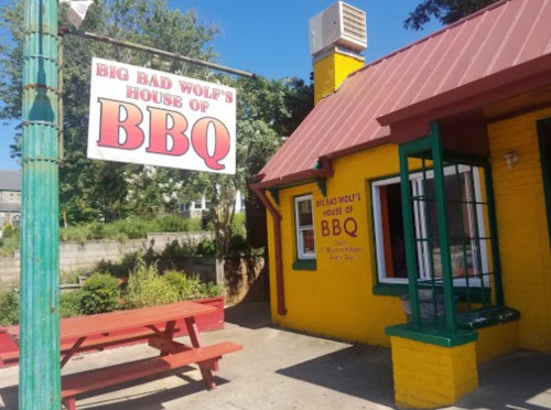 A colorful building with a red roof and a sign reading "Big Bad Wolf's House of BBQ" in a sunny outdoor setting.