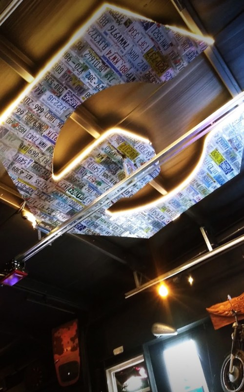 A ceiling decorated with colorful license plates arranged in a large "C" shape, illuminated by soft lighting.