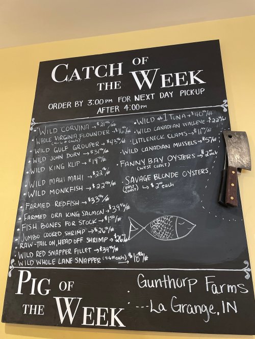 Chalkboard menu listing seafood specials and farm products, including prices and ordering details for pickup.