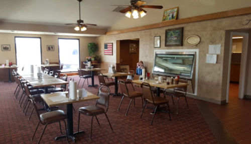 Interior of a casual dining restaurant with empty tables, ceiling fans, and decor including an American flag.