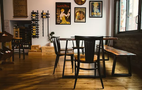 A cozy restaurant interior with wooden tables, chairs, and vintage wall art, featuring a warm, inviting atmosphere.
