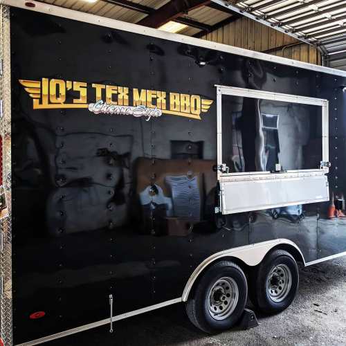A black food trailer with "IQ's Tex Mex BBQ" logo, featuring a serving window and shiny exterior.