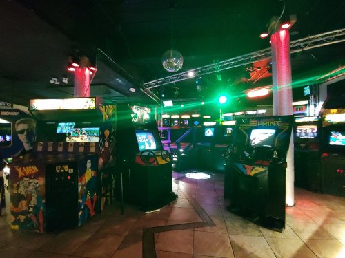 A vibrant arcade filled with classic game machines, colorful lights, and a disco ball reflecting in a lively atmosphere.