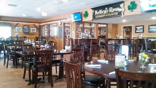 Interior of a restaurant with wooden tables and chairs, decorated for St. Patrick's Day with green accents.