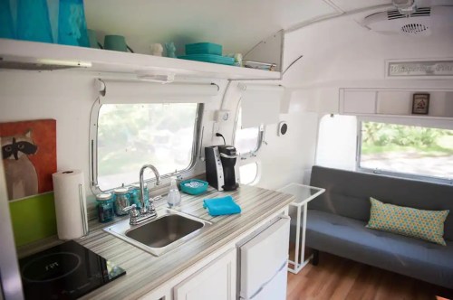 Cozy interior of a modern camper with a kitchenette, seating area, and bright decor.