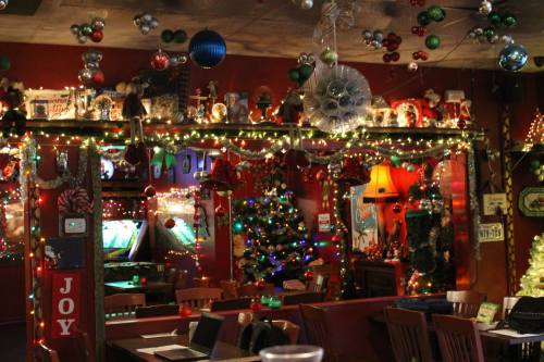 A festive bar decorated with colorful lights, ornaments, and a Christmas tree, creating a cheerful holiday atmosphere.