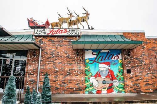 A festive building with a mural of Santa playing guitar and reindeer on the roof, decorated for the holidays.