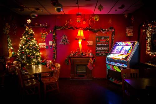 Cozy room decorated for the holidays, featuring a Christmas tree, festive lights, and a vintage jukebox.