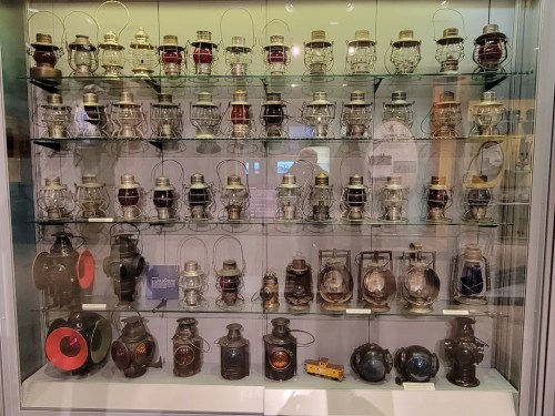 A display case filled with various vintage lanterns, showcasing different colors and designs.