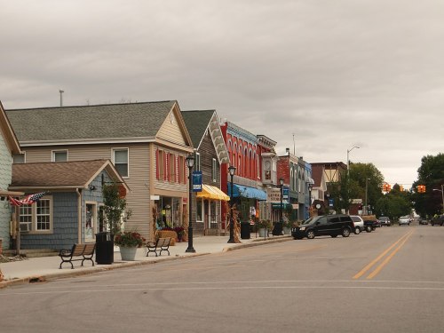 A quaint street lined with colorful shops and benches under a cloudy sky.