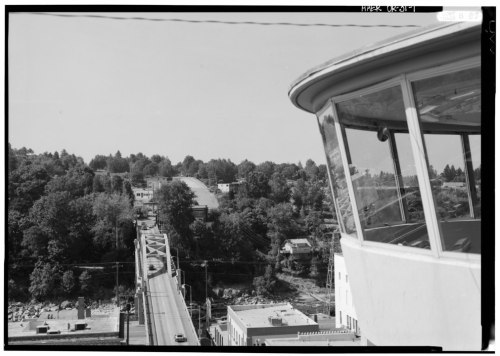 View from a control tower overlooking a bridge and tree-lined landscape in a black and white photograph.