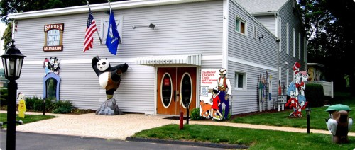Entrance of the Barker Cartoon and Comic Museum, featuring colorful cartoon characters and flags outside.