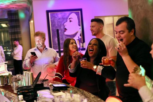 A group of people enjoying drinks at a bar, with colorful lights and a lively atmosphere.