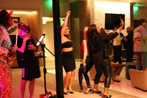 A lively scene with people dancing and enjoying live music in a stylish venue, with colorful lighting and a festive atmosphere.