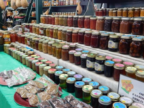 A display of colorful jars filled with various preserves and candies on a table at a market.
