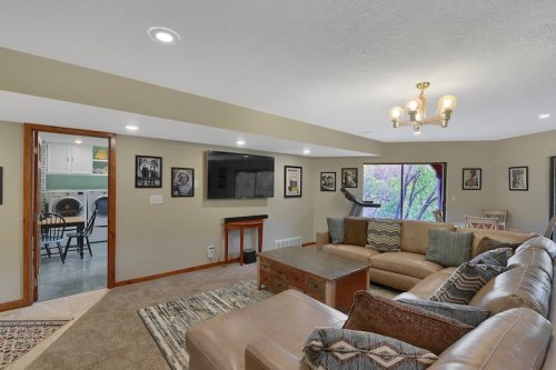 Cozy living room with a large sectional sofa, TV, and artwork on the walls, leading to a laundry area.