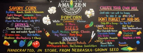 Chalkboard menu featuring popcorn flavors, snacks, drinks, and mix options at A-MA-ZEN Popcorn & Snacks.