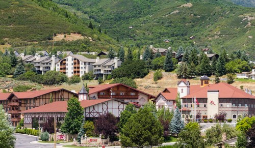 A scenic view of a mountain village with traditional architecture and modern buildings surrounded by lush greenery.