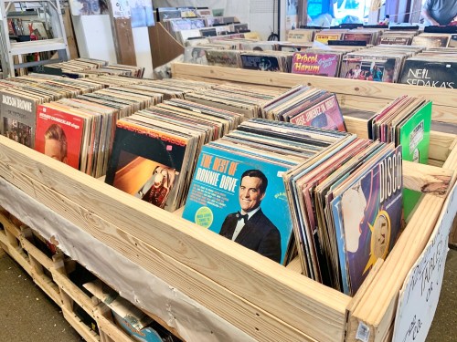 A wooden crate filled with various vinyl records, showcasing colorful album covers.
