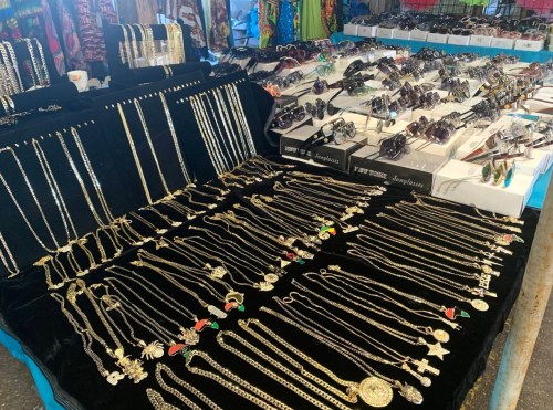 A vibrant market display featuring various gold necklaces and accessories on black fabric.