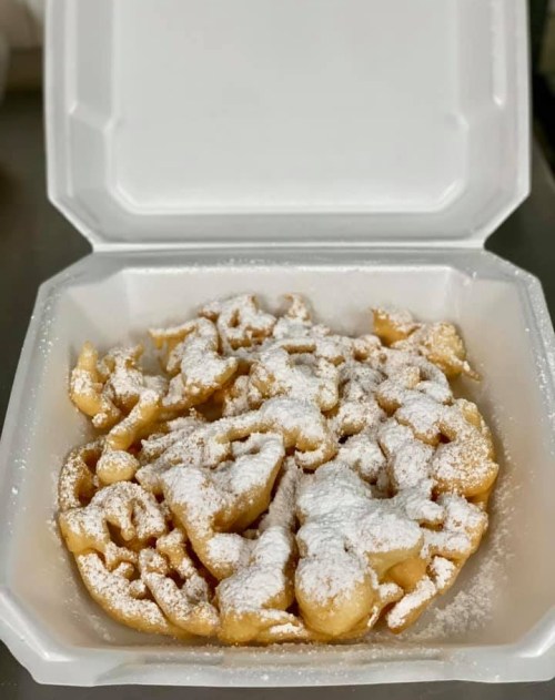 A takeout container filled with a dusted funnel cake, showcasing its crispy, golden-brown texture.