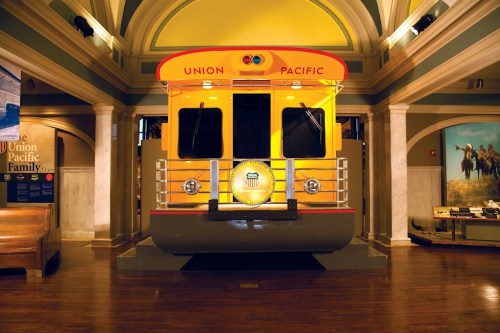 A vintage Union Pacific train car display in a museum, featuring bright yellow colors and a circular logo.