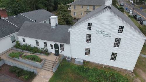 Aerial view of the American Quack Doctor Museum, featuring a white building with a sloped roof and surrounding greenery.