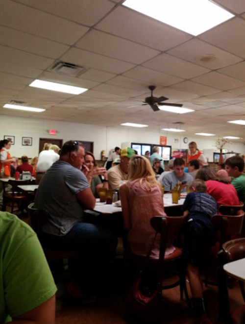 A busy restaurant filled with people dining and socializing at tables, with a casual atmosphere and bright lighting.
