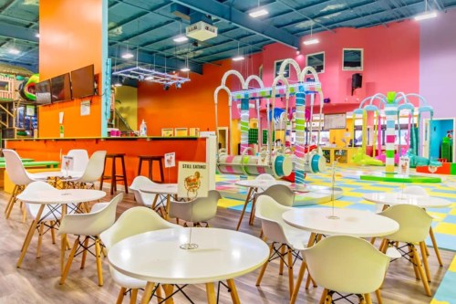 Bright indoor play area with colorful structures, tables, and chairs, designed for children’s activities and fun.