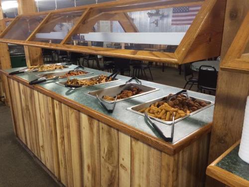 A buffet with various trays of food, including meats and appetizers, in a rustic dining area.