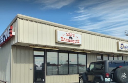 Exterior of a barbecue restaurant with a sign reading "Mac's Barbeque" and a parked black Jeep in front.
