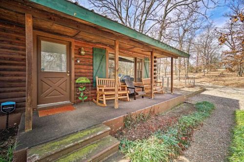 A rustic cabin porch with rocking chairs, surrounded by trees and a gravel path.