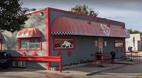 A colorful diner with a red and gray exterior, featuring a striped awning and checkered accents.