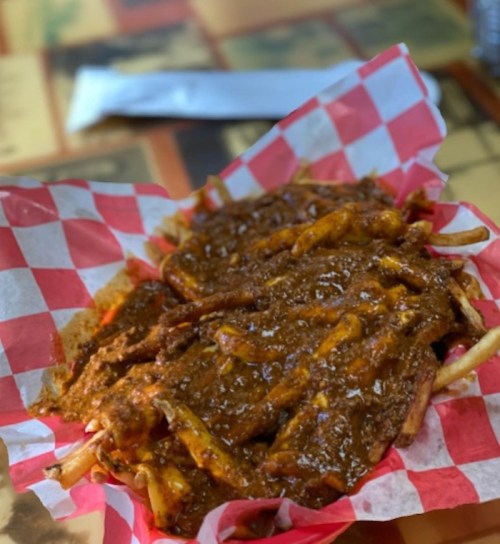 A plate of ribs covered in a rich sauce, served on a red and white checkered paper.