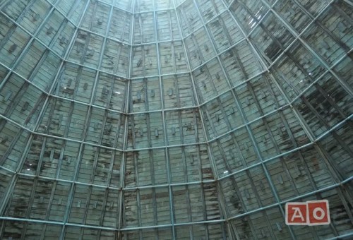 Interior view of a large, glass-paneled structure with a geometric design and weathered wooden panels.