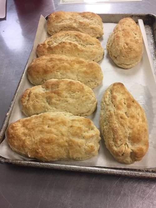 Freshly baked scones on a parchment-lined baking tray, golden brown and fluffy.