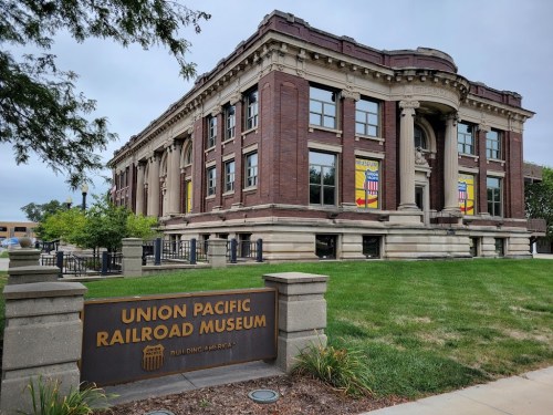 Historic Union Pacific Railroad Museum building with banners, surrounded by green grass and trees.